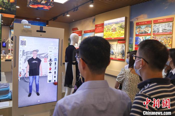 图为几位参观者在体验智能试衣镜，该设备使用MR技术，将服装的虚拟影像“穿”在镜中的人像上。　刘力鑫 摄